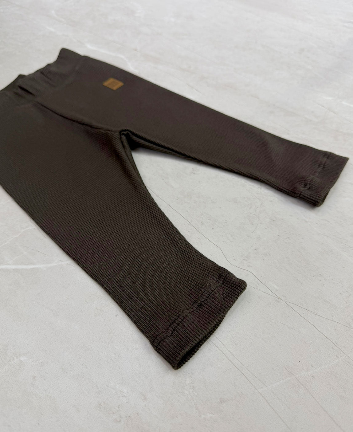 Detalhes da Calça Slim Canelada Liso Café - ribana elástica, cós com elástico macio sem cadarço, etiqueta de courino - marrom café escuro - MiniMalista Baby