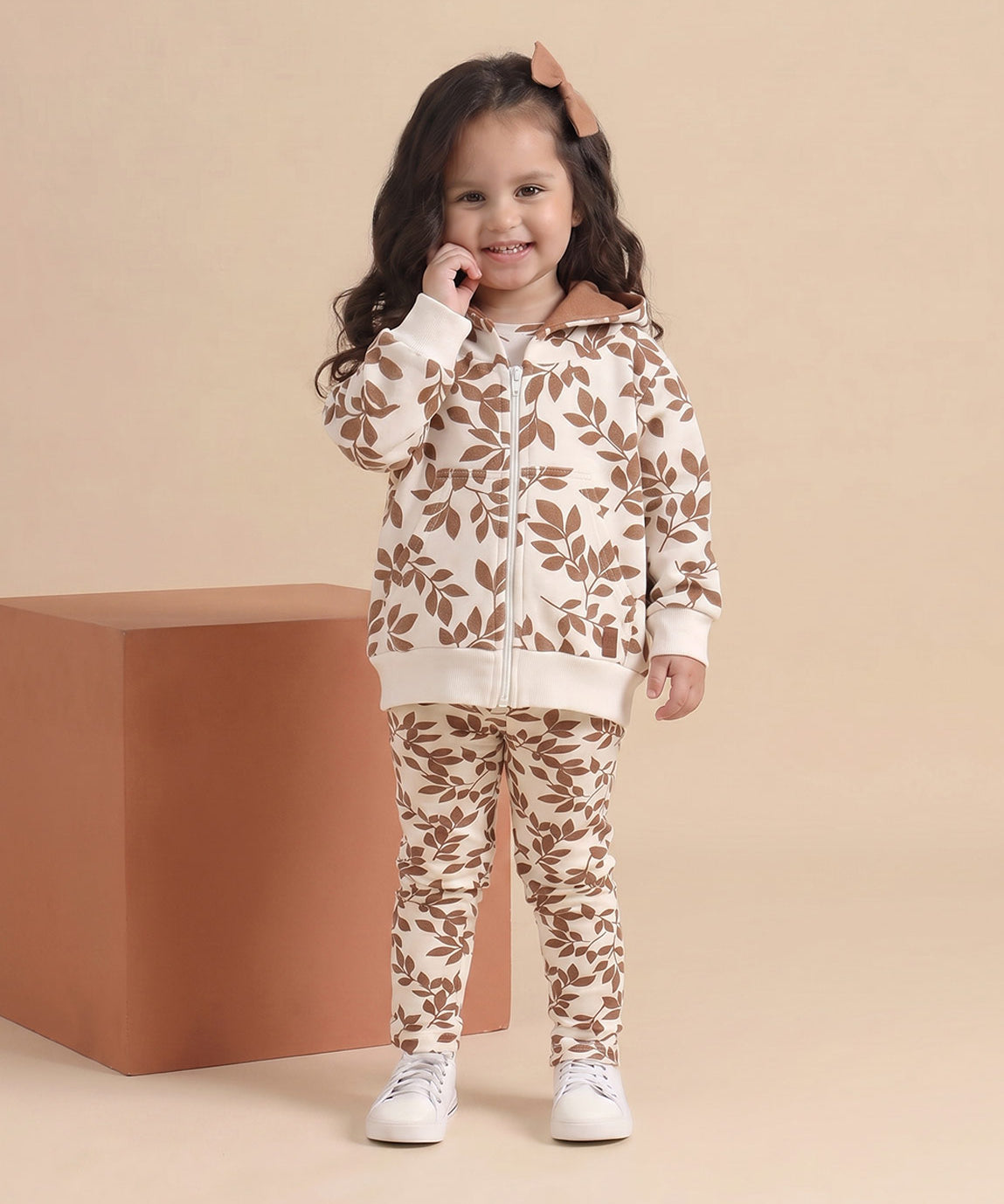 Detalhe da estampa Laurel folhagem de louro allover em tons terrosos sobre caramelo, no Conjunto Casaco Moletom + Legging da MiniMalista — 100% algodão premium, look pronto de outono e inverno pra menina