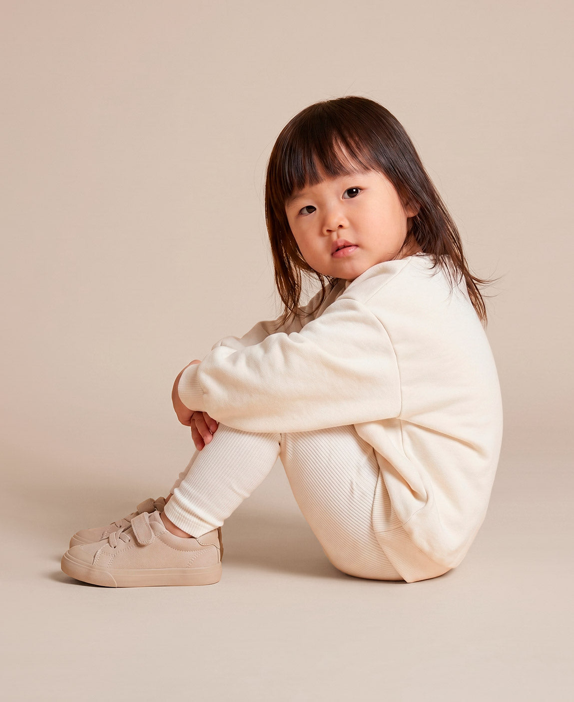 MiniMalista Conjunto Moletom + Calça Canelada Liso Branco Off vestido em criança. Look all-white elegante infantil 100% algodão, moletom peluciado e calça canelada slim no mesmo tom, conjunto unissex menino e menina.
