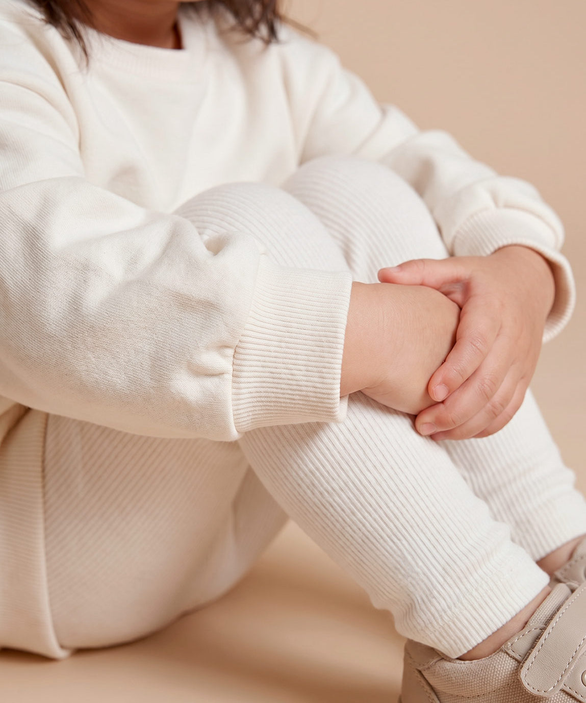 MiniMalista Conjunto Moletom + Calça Canelada em Branco Off vista costas. Moletom oversized soltinho + calça canelada slim, look infantil monocromático unissex, estética escandinava minimalista para bebê e criança.