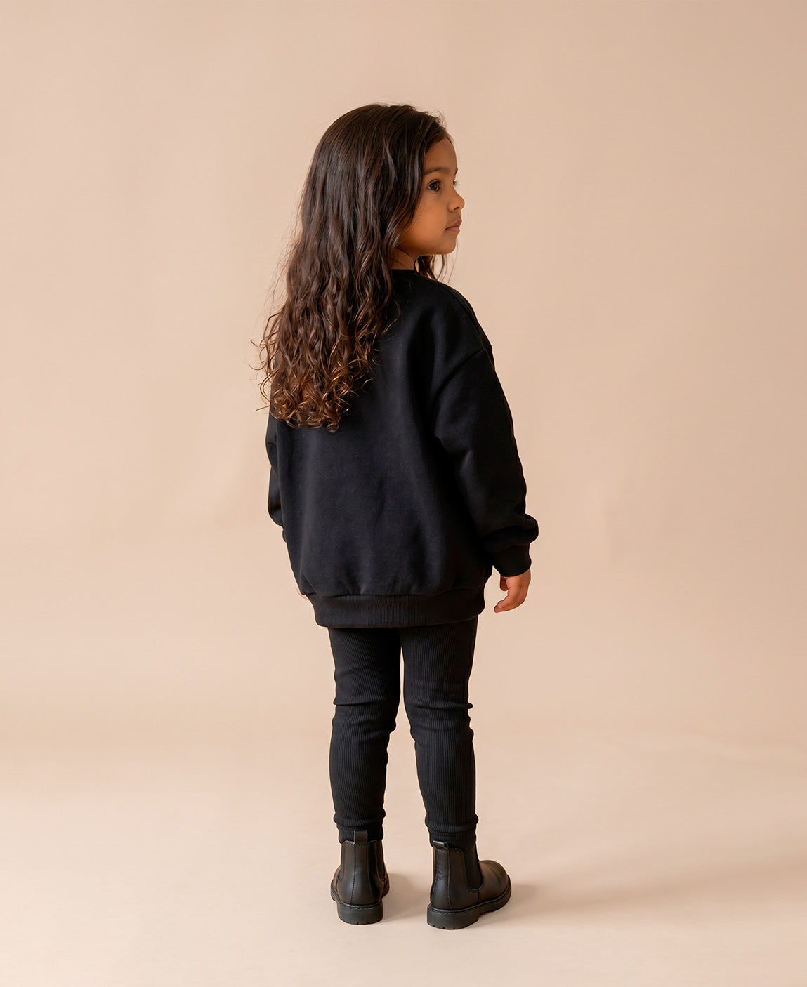 MiniMalista Conjunto Moletom + Calça Canelada Liso Preto vestido em criança. Look elegante infantil 100% algodão, moletom peluciado e calça canelada slim no mesmo tom, conjunto unissex menino e menina.