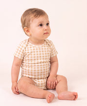 Bebê vestindo o Body Manga Curta Vichy Bege MiniMalista, vista frontal. Body de bebê em algodão com gola americana, xadrez vichy bege, unissex menino e menina.