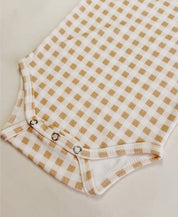 Detalhe frontal do Body Manga Curta Vichy Bege MiniMalista com os botões entrepernas. Body de bebê (onesie) em algodão, xadrez vichy bege, unissex menino e menina.